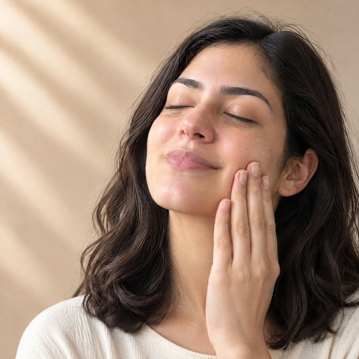 Gesto de cuidado facial sobre la piel limpia y seca.